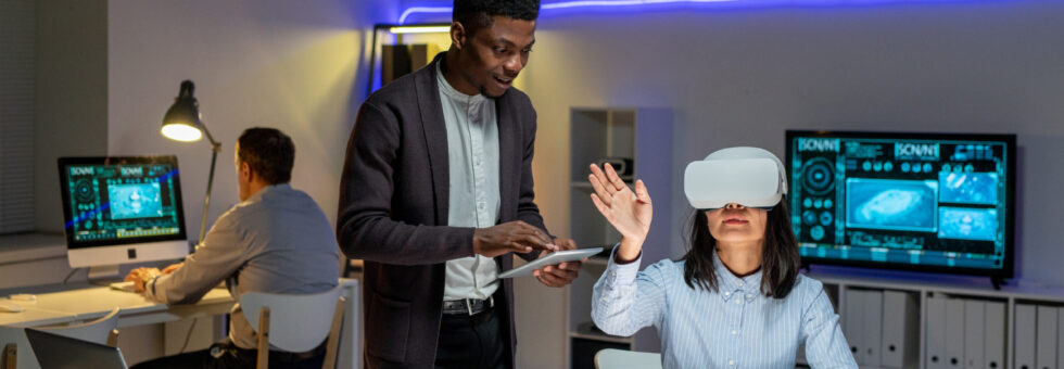 African American employee synchronizing tablet virtual reality headset of Asian colleague while they designing car in 3D